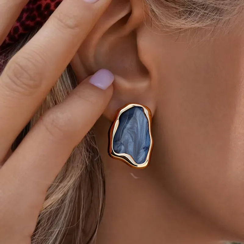 Close-up of a person wearing a gold and blue stone earring.