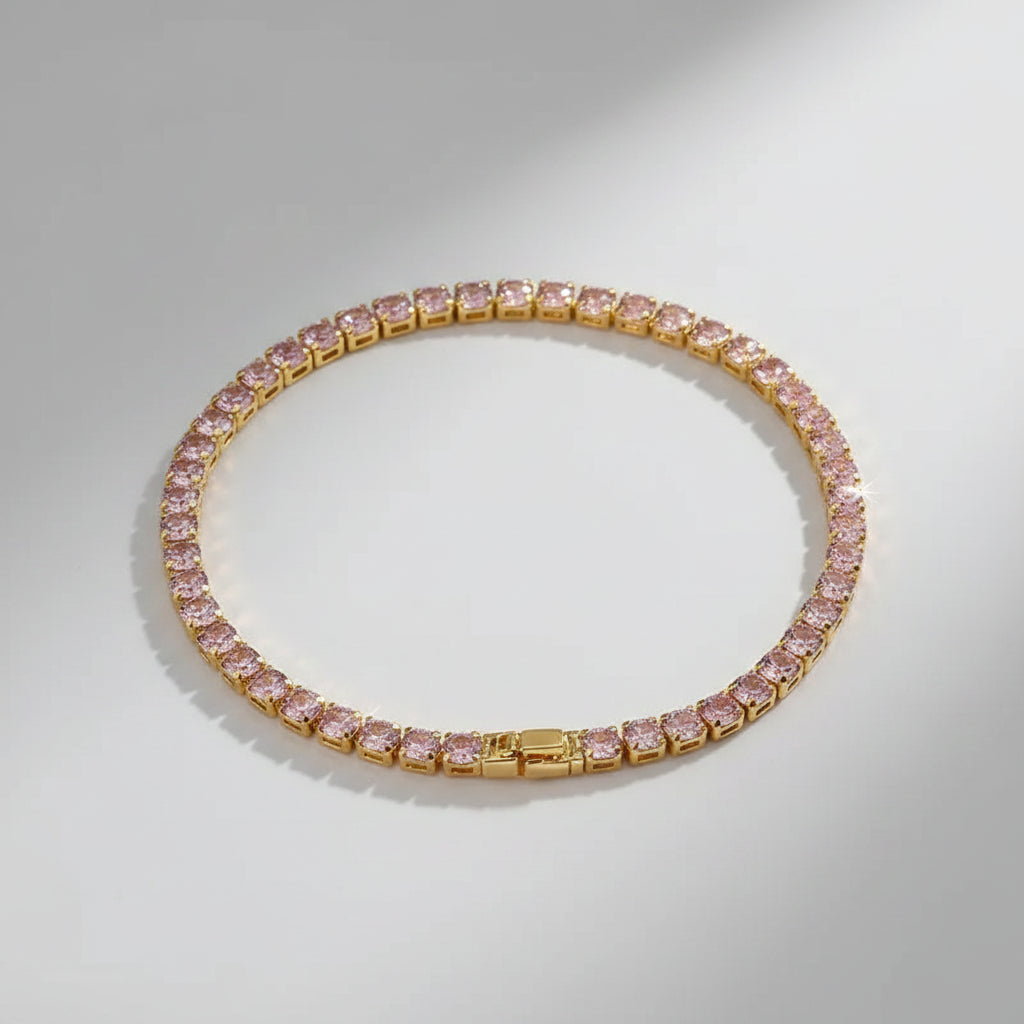 Gold bracelet with pink gemstones on a beige surface